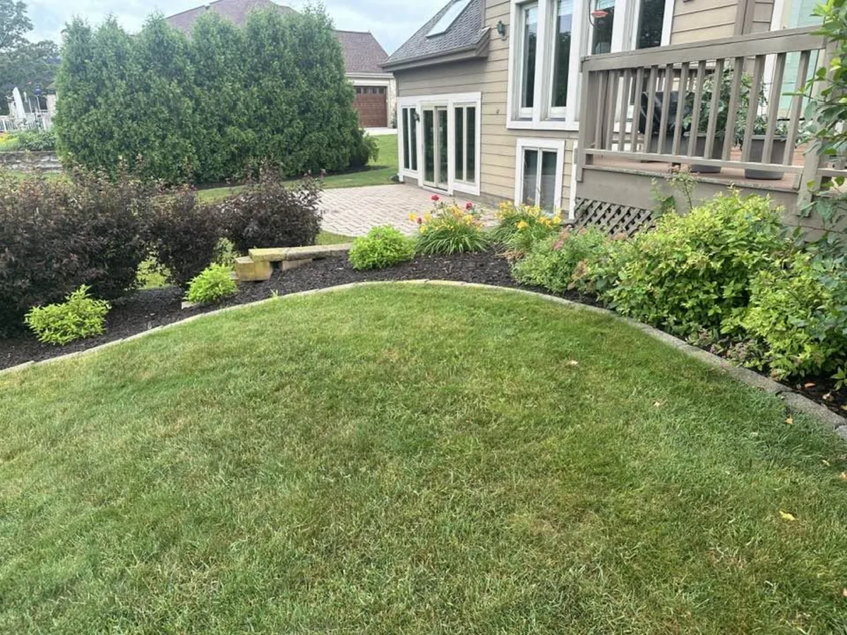 Front lawn and landscaped beds along the side of a two story home
