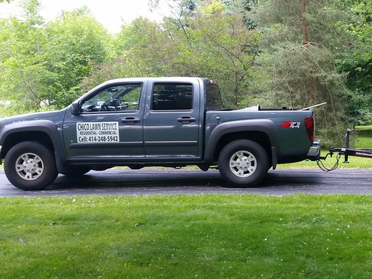Lawn care service truck with a trailer hitch parked along a residential street