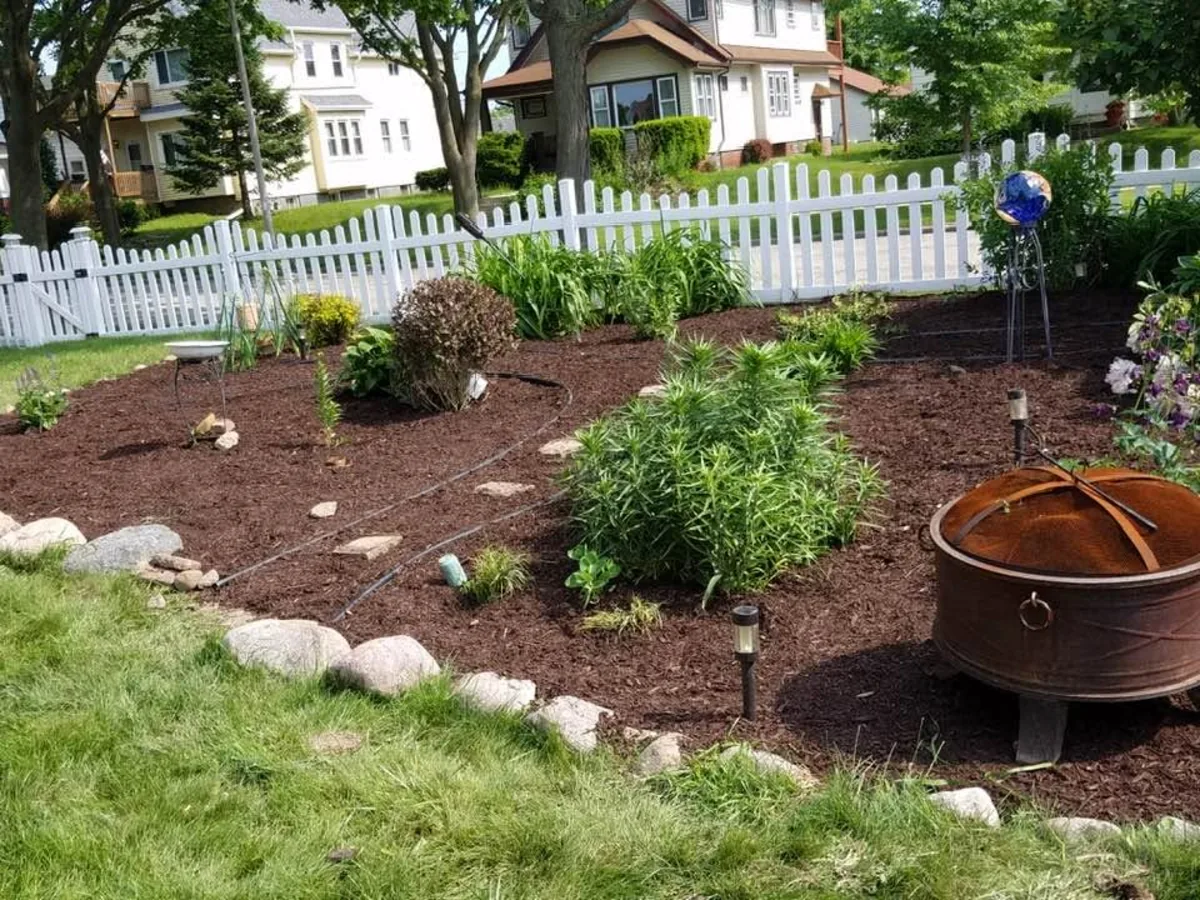 Perennial planting bed with fresh mulch, boulders and a fire pit