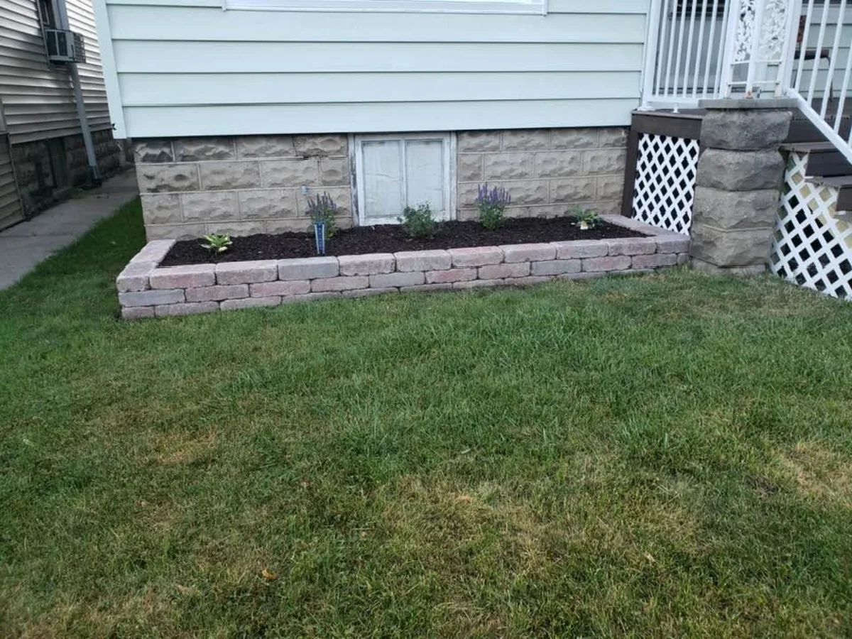 Small block retaining wall bed with fresh mulch and new plantings
